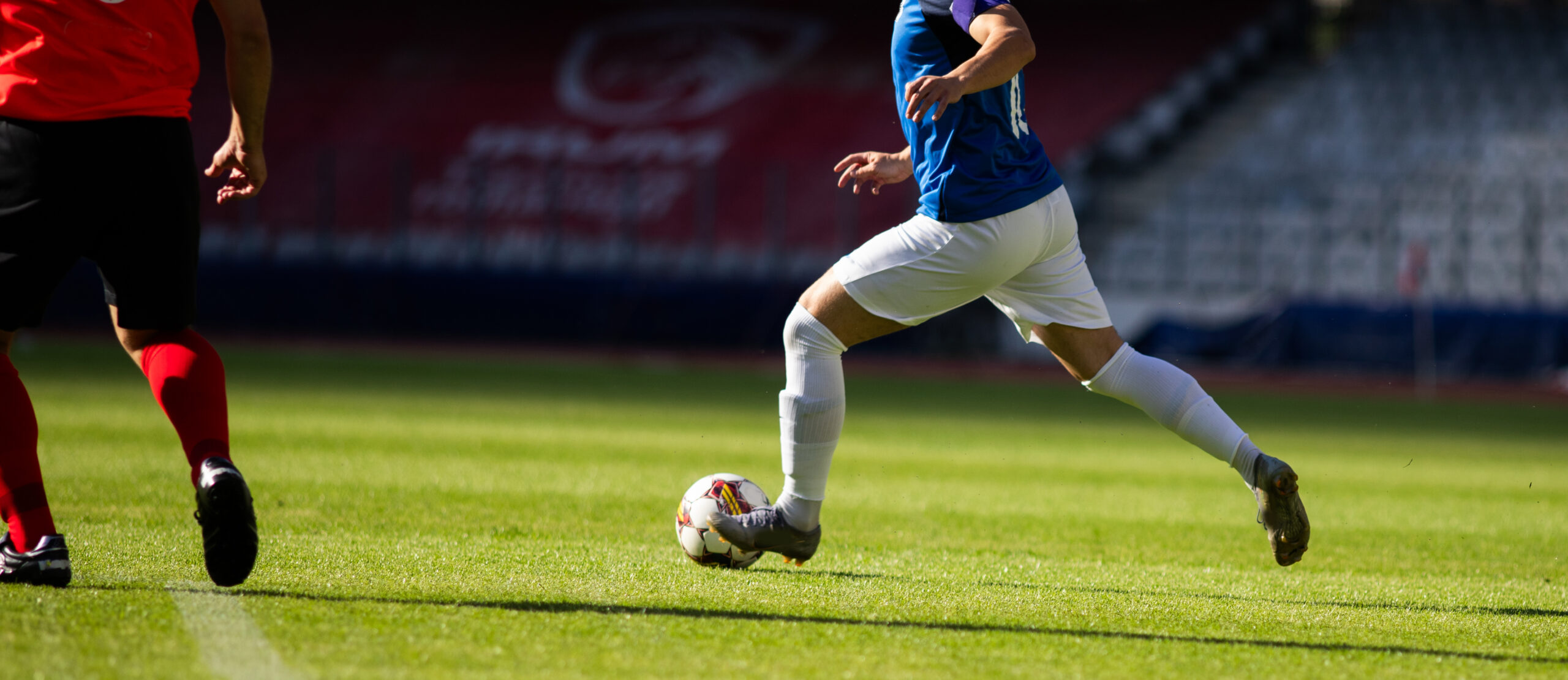 Soccer players running and dribbling with ball on green field.